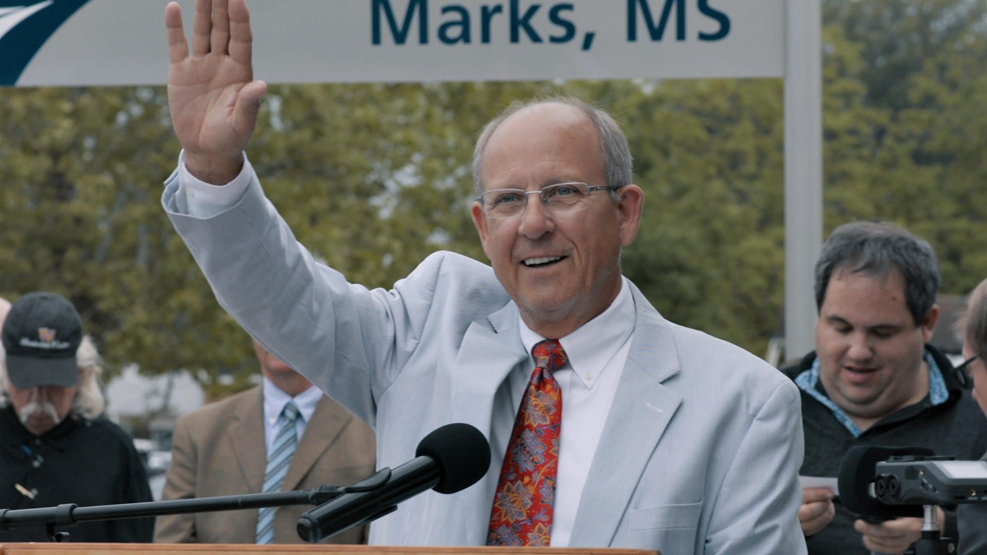 Photo of man at podium, waving